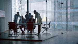 technology industry employees in office discussing dfars compliance regulations around a computer at desk