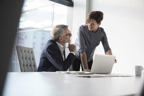 Businessman and businesswoman discussing email security over a laptop in office