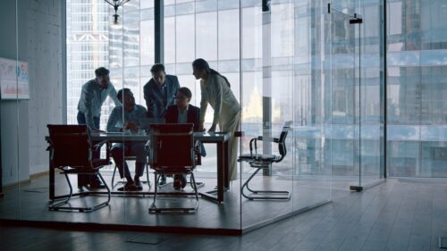 technology industry employees in office discussing dfars compliance regulations around a computer at desk