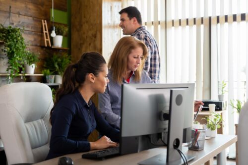 office workers on computer ensuring they're cmmc compliant